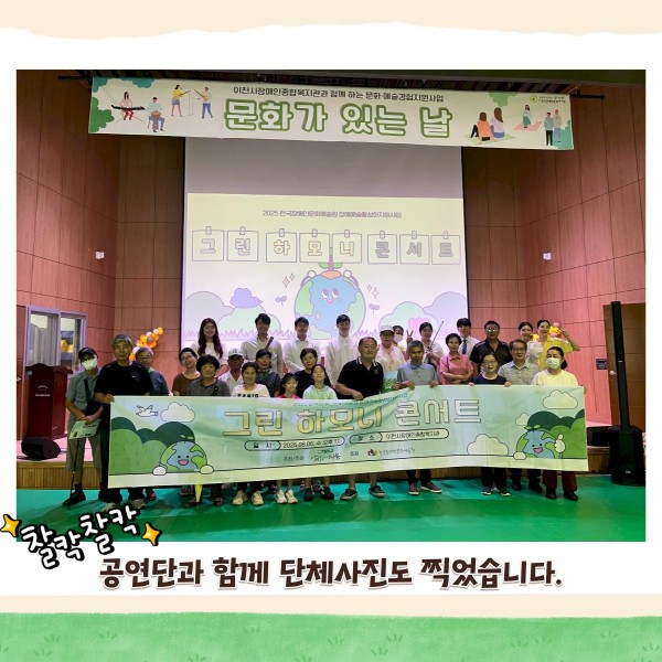 무대 단상 밑에서 참여자들과 공연단이 그린하모니콘서트라고 적혀있는 현수막을 들고 단체사진을 촬영하고 있다.